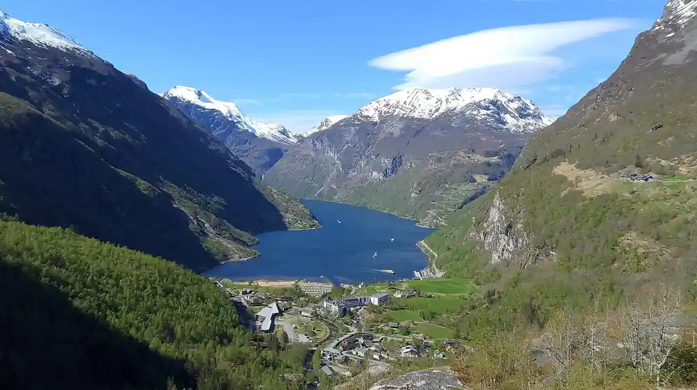 Alpine valley with lake village and snowy mountain peaks