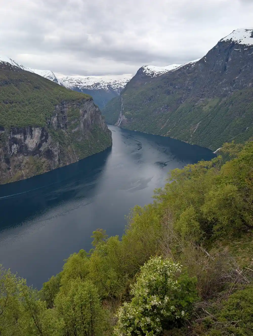 Deep fjord between tall mountains with waterfall visible