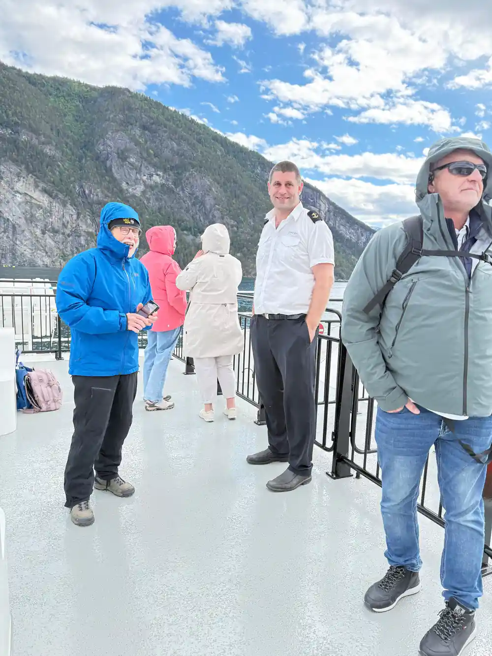 Group of people standing on boat deck with mountains