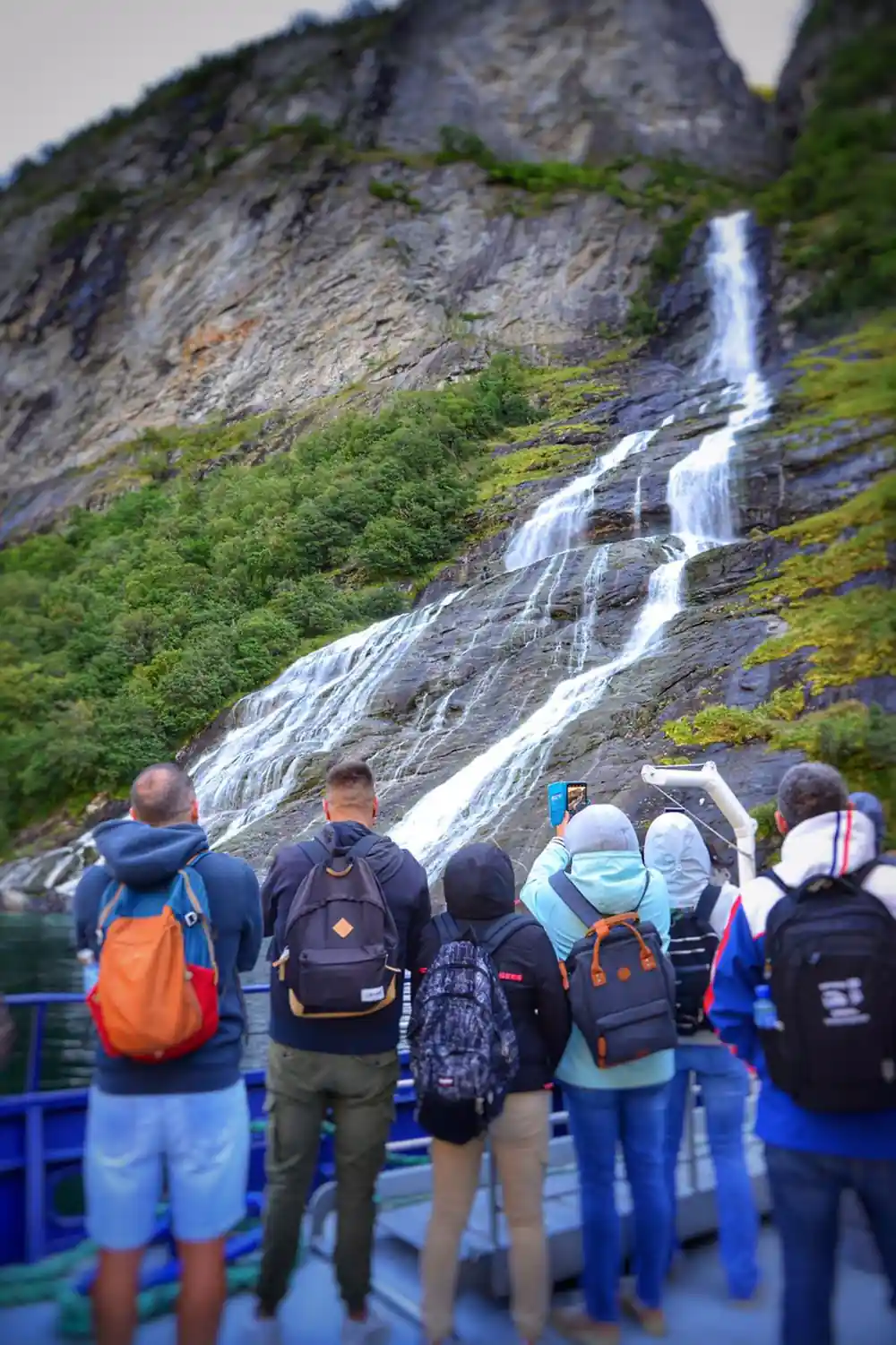 Group viewing tall waterfall from boat deck