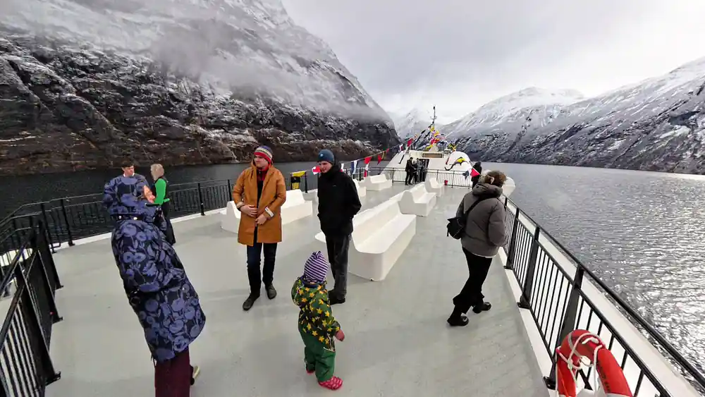 Passengers standing on ferry deck in snowy mountains