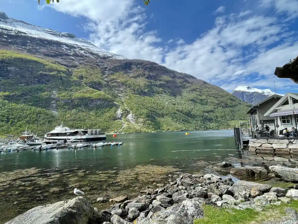 Scenic lake with boats, snowy peaks and green mountainside