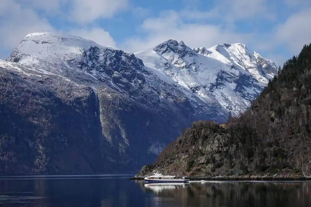 Snow-capped mountain peaks above dark fjord water