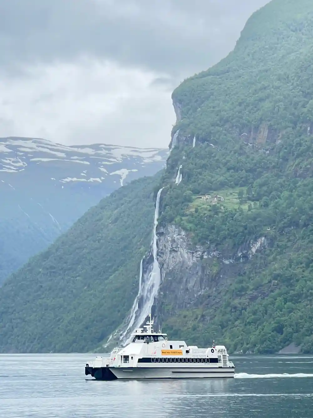 Steep green mountainside with long thin waterfall streaks