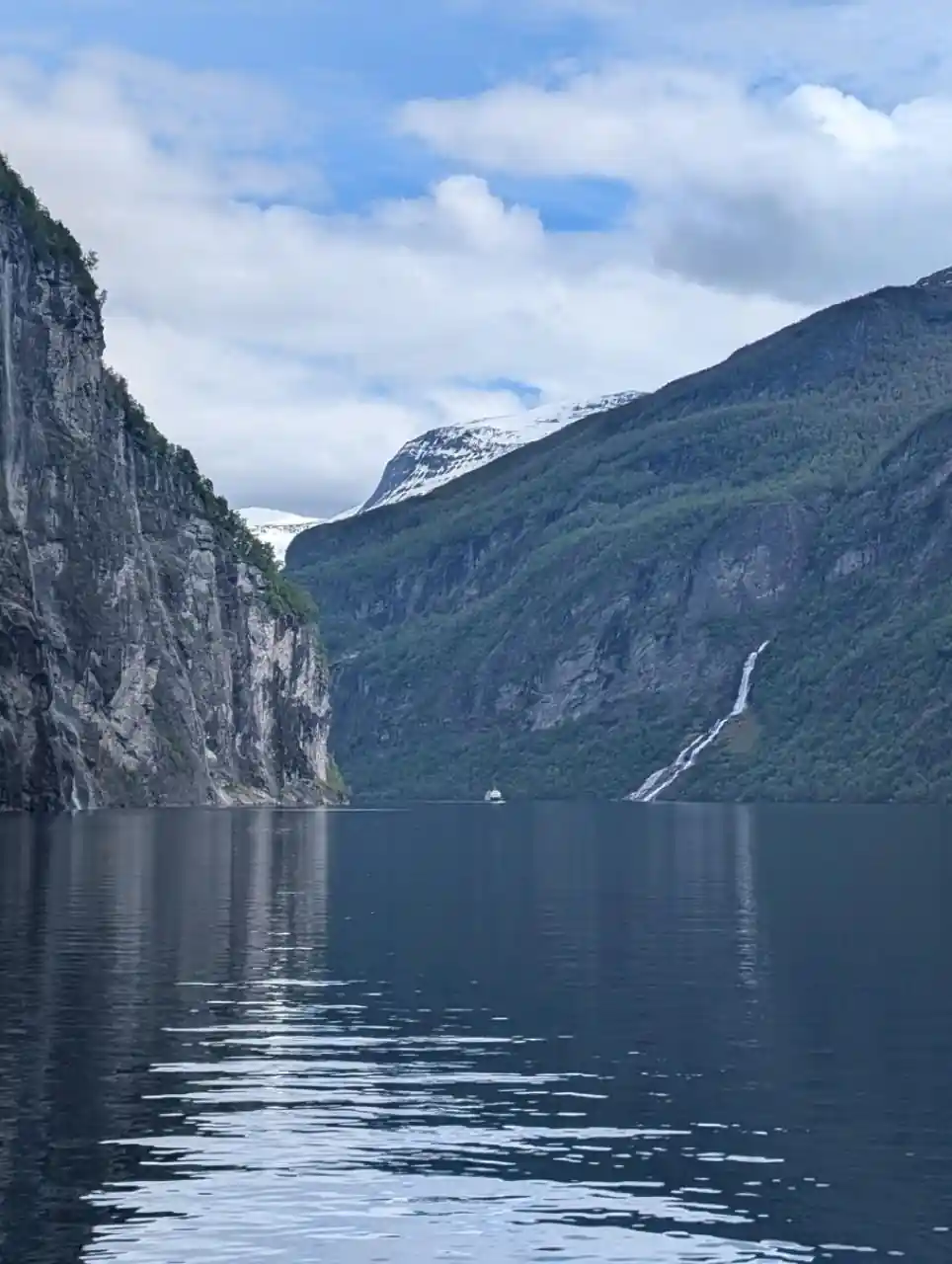 Steep rocky cliffs framing narrow fjord with small boat