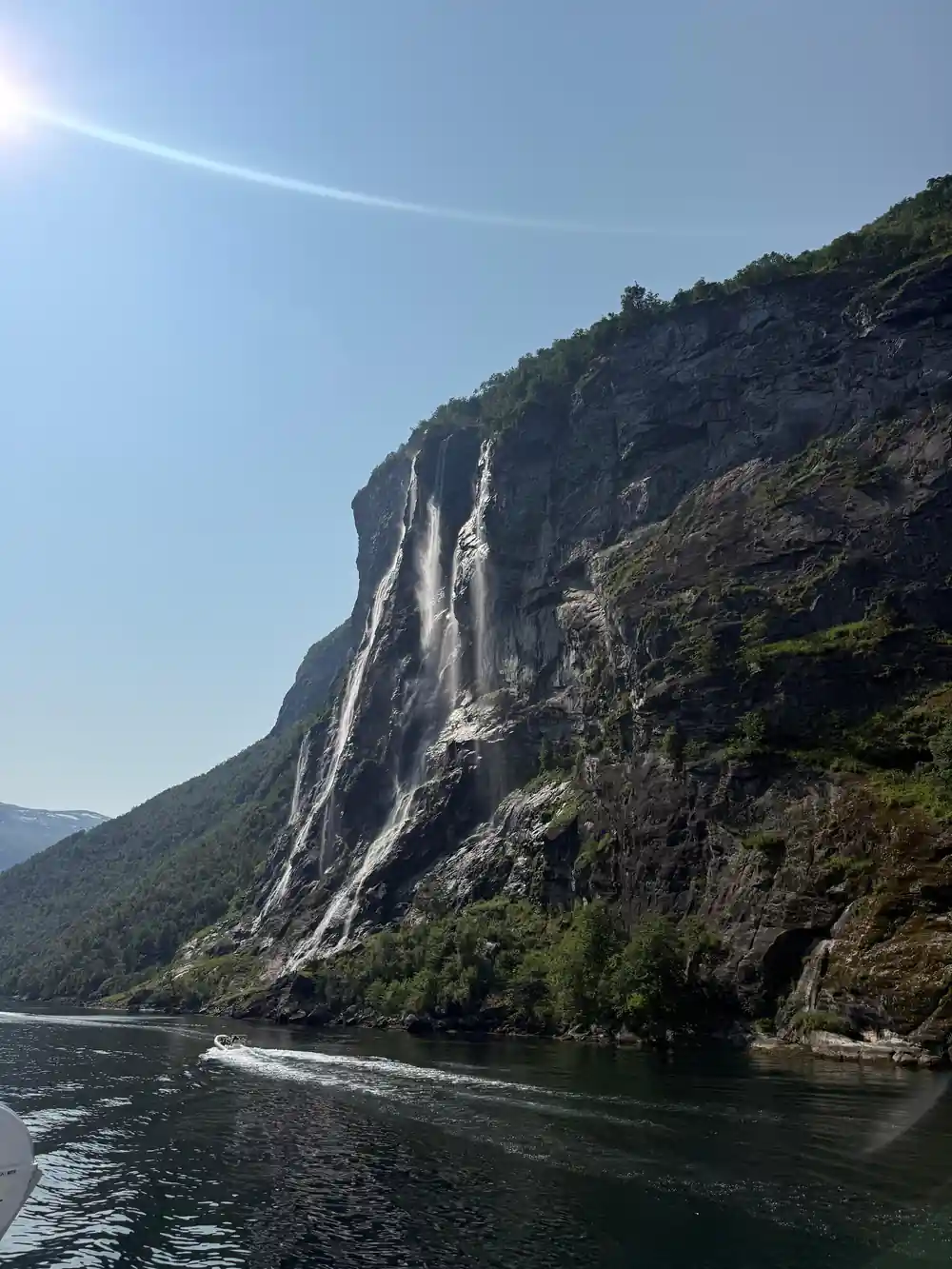 Tall waterfall dropping from cliff into fjord lake