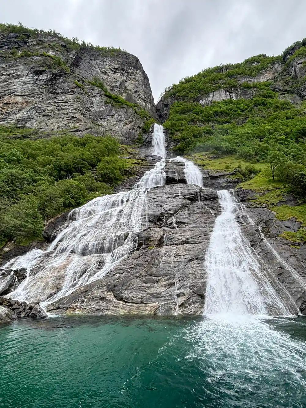 Tall waterfall flowing over rocky cliff into turquoise pool
