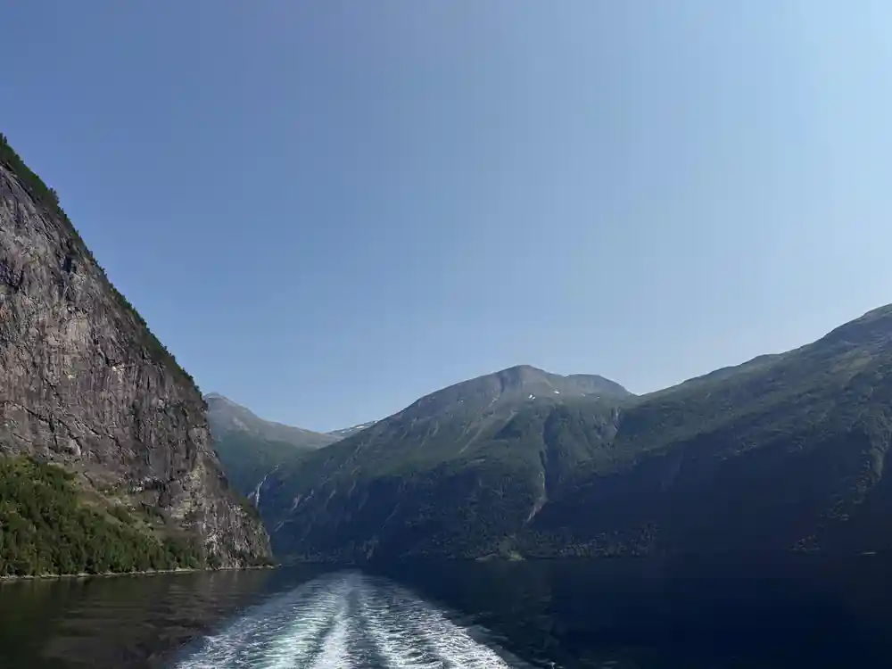 Wake from boat moving through mountain-lined deep fjord