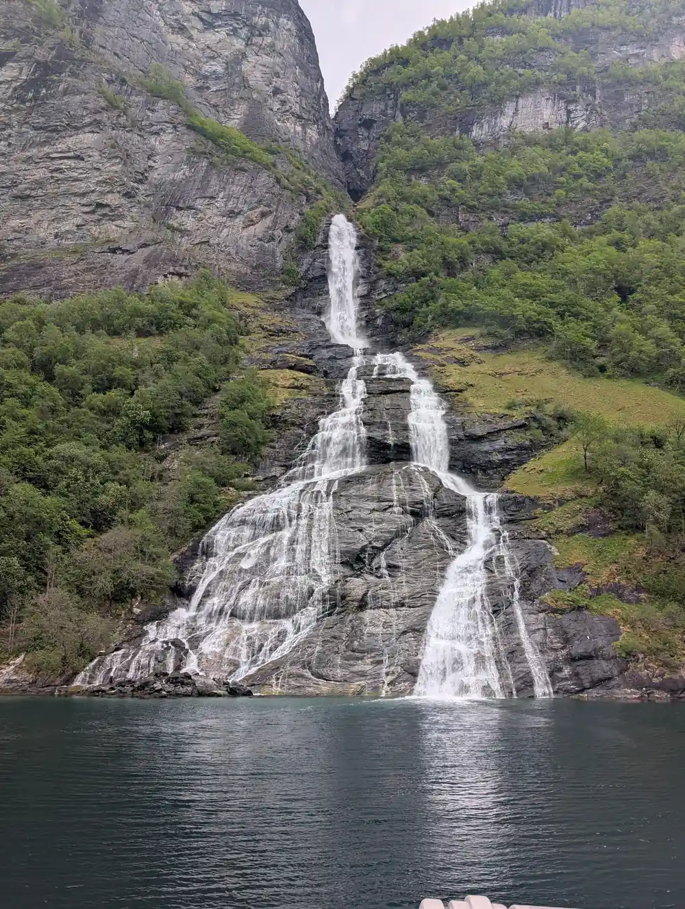 Waterfall cascading down rocky mountainside into fjord